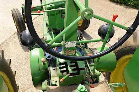 De werkplek van de John Deere B met rechts onder meer de handkoppeling. De rode knop links onder op de plek waar bij normale trekkers de koppeling zit, is de startknop of eigenlijk het startpedaal. De bedoeling is dat je de knop met de voet indrukt.