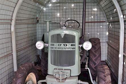 De M.A.N. staat in een nissenhut die ooit mintgroen is geverfd, bijna exact dezelfde kleur als de trekker zelf.