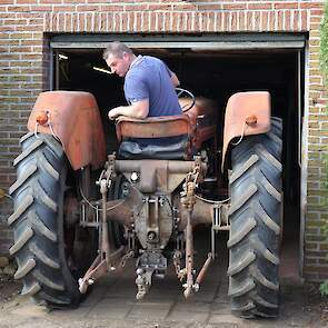 Dennis rijdt de MF Super 90 naar buiten. Hij kan maar net door de deur.