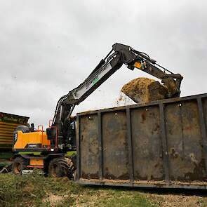 Een kraan schept de mais vervolgens over in een silagewagen.